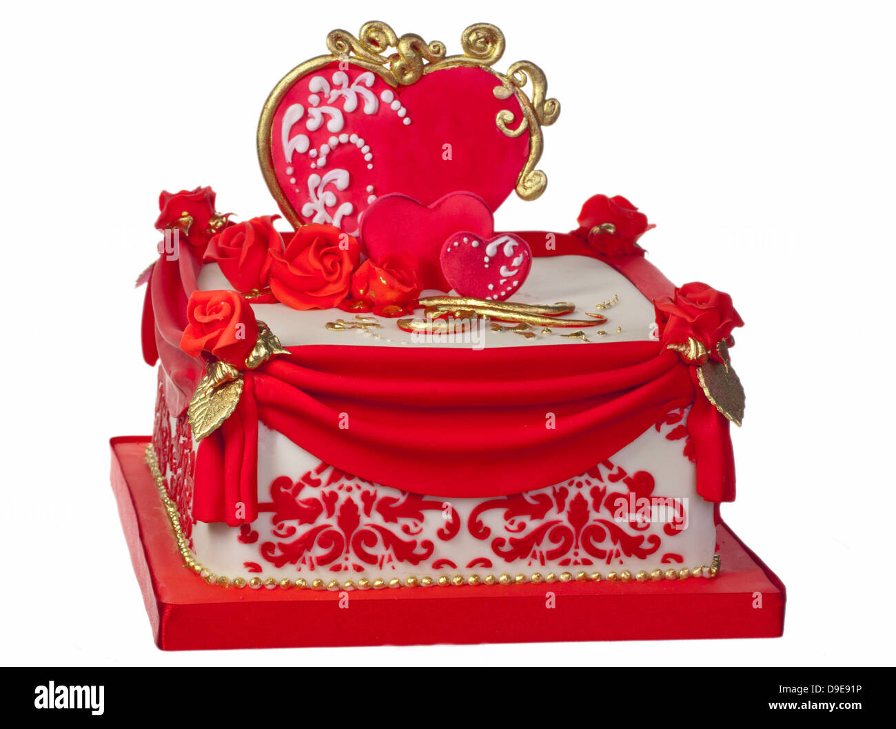 Celebration iced cake in red, white and gold  decorated with hearts and roses. Stock Photo