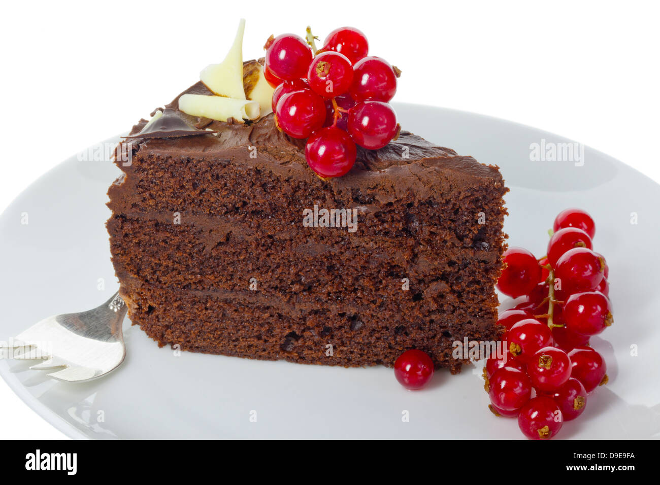 Slice of dark chocolate cake decorated with red fruit isolated on white. Stock Photo