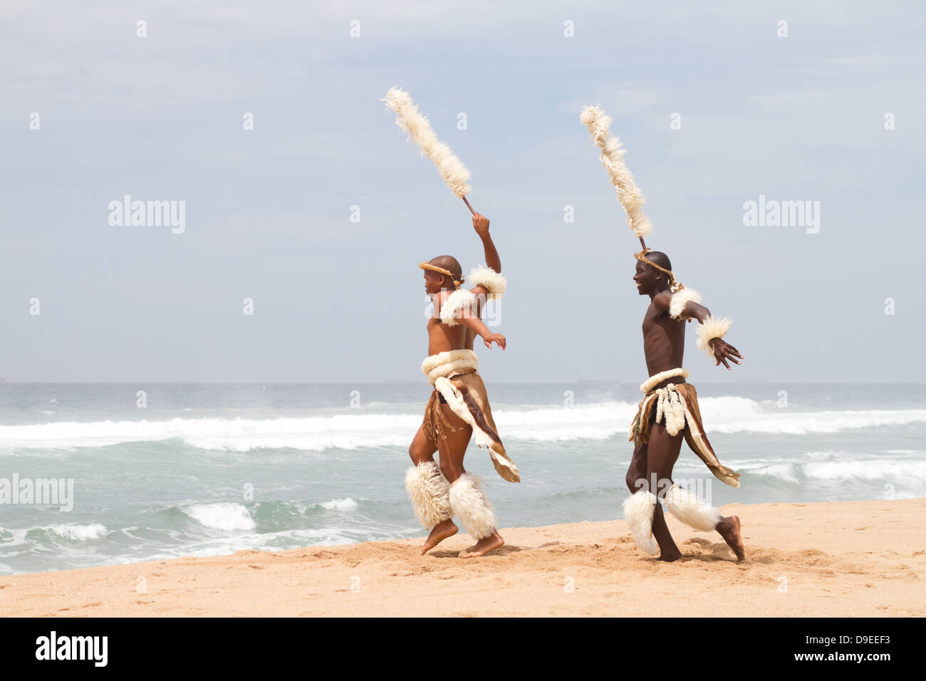 two African Zulu men dancing on beach Stock Photo