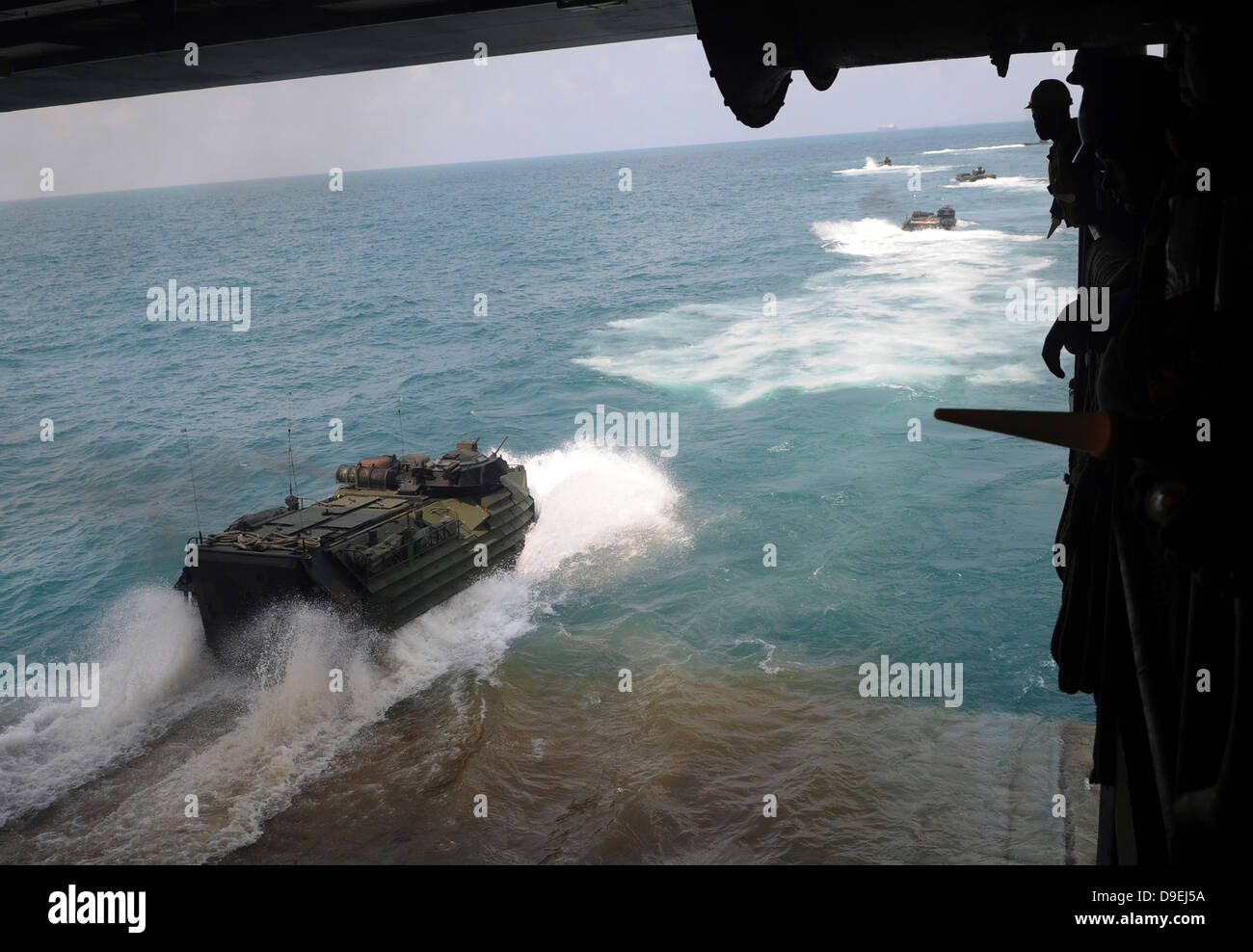 Amphibious assault vehicles exit the well deck of USS Denver. Stock Photo