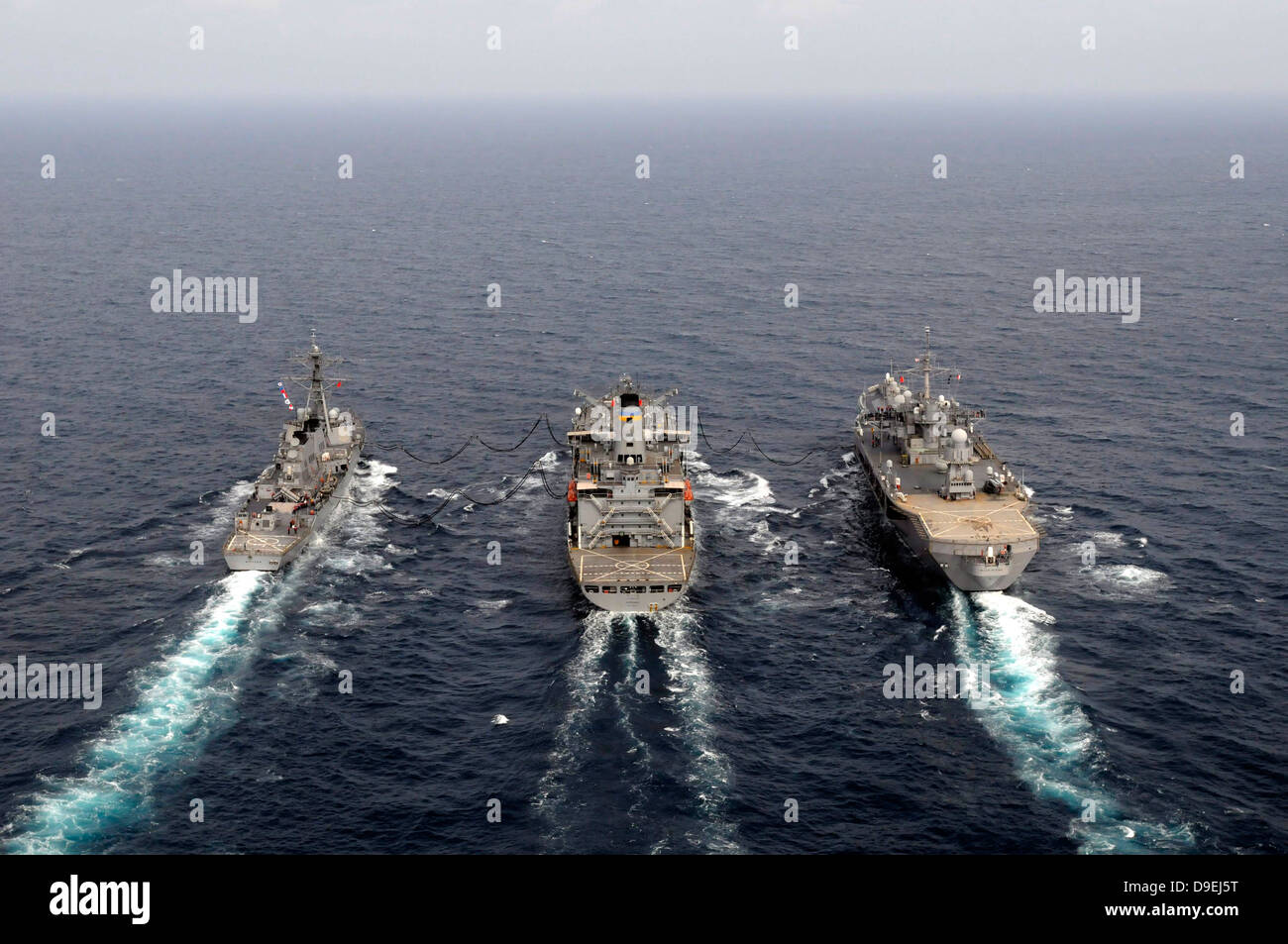 Military ships conduct an underway replenishment in the Pacific Ocean. Stock Photo