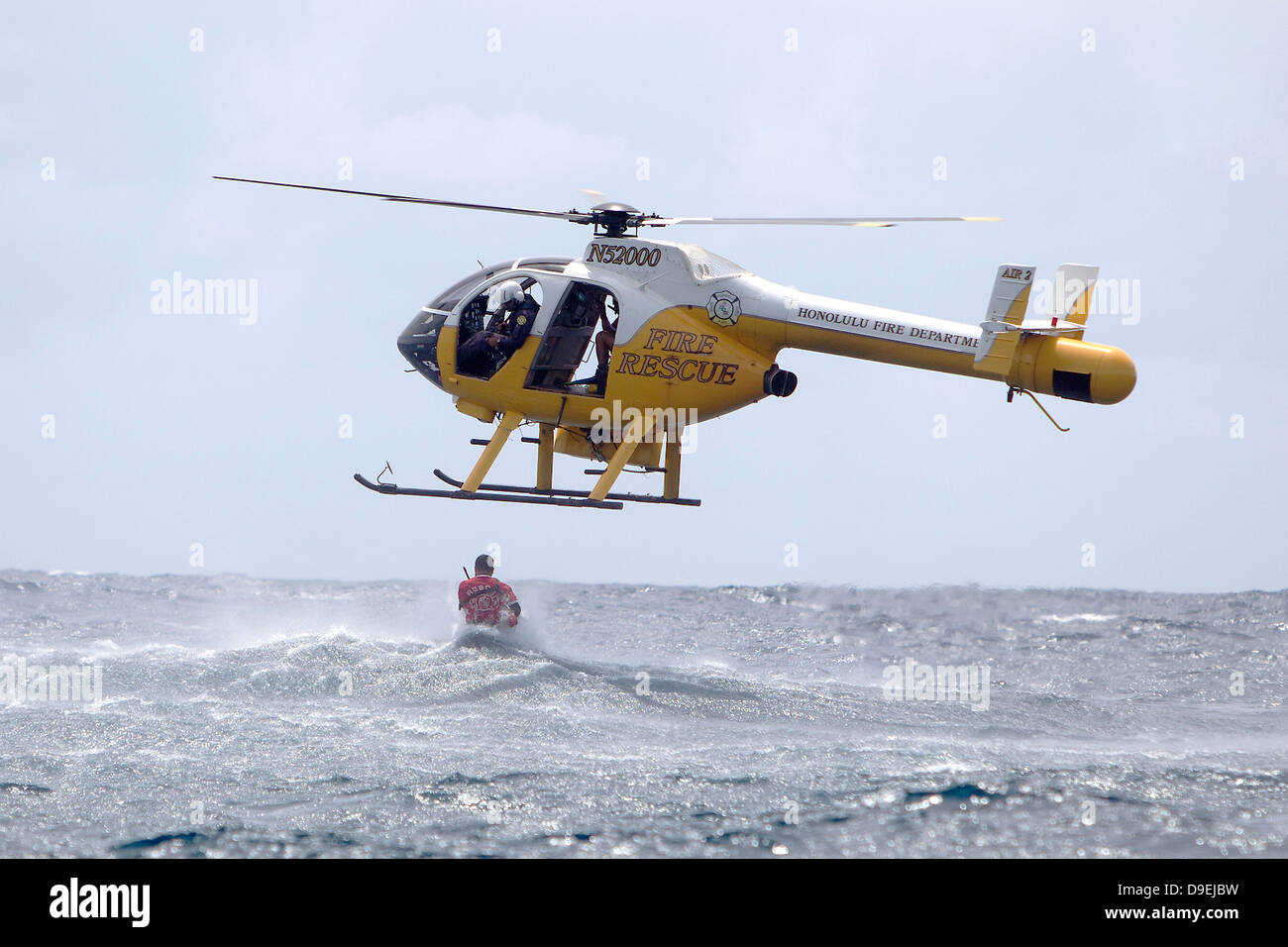 A Honolulu Fire Department rescue helicopter drops a rescue swimmer in respone to US Marine Corps pilots simulating a downed aircraft during annual mishap drill training for surviving a crash June 11, 2013 in Kaneohe Bay, Hawaii. Stock Photo