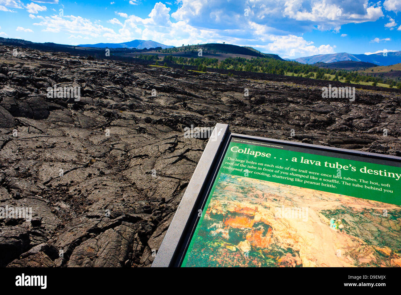 Lava fields on partly cloudy day at Craters of the Moon National Monument, with sign in foreground discussing lava tubes Stock Photo
