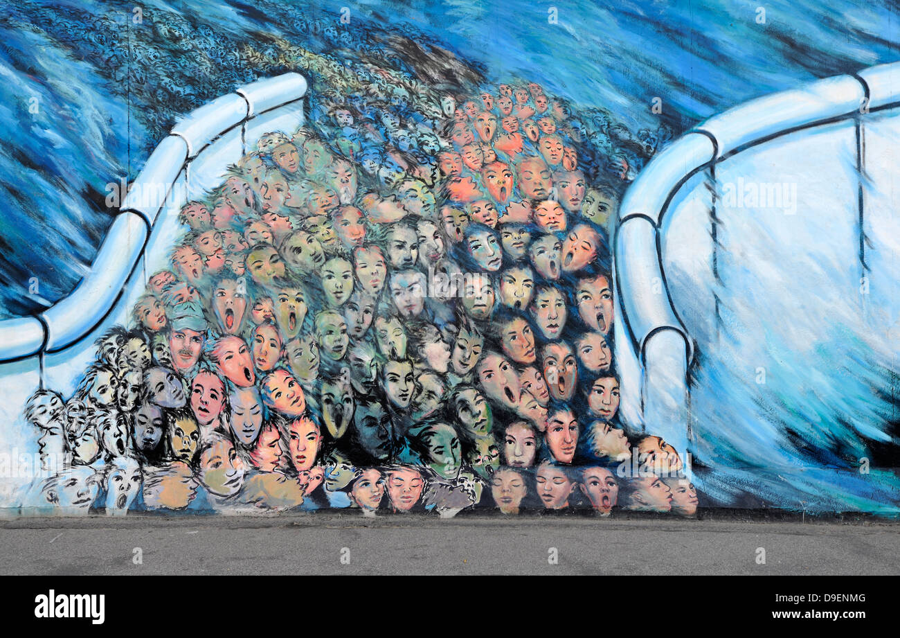 Art and Berlin Wall human masses break through the Berlin Wall Fall of the Wall painting in a rest of the Berlin Wall East Side Stock Photo