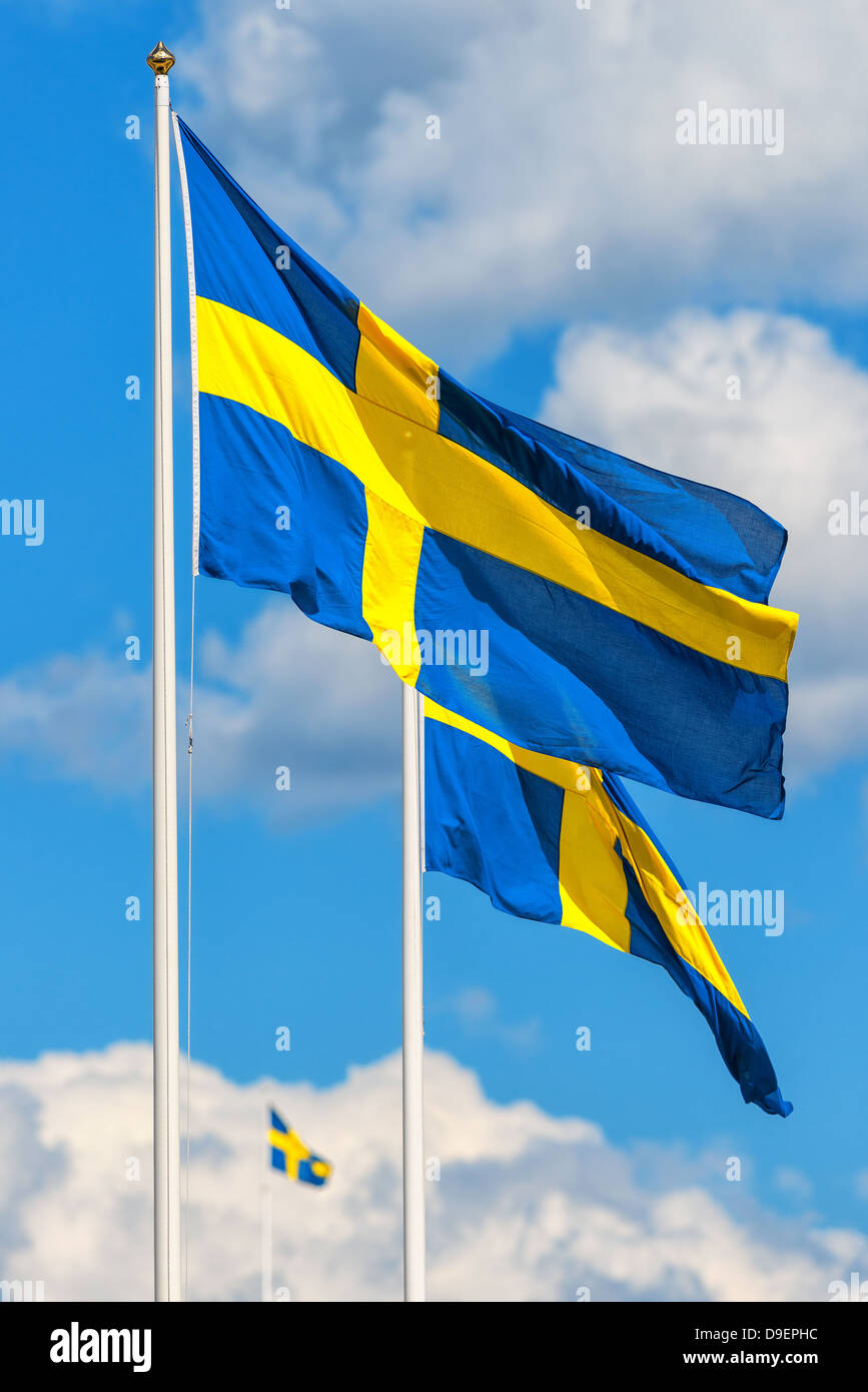 Three Swedish flags with the flag in front in focus on a typical summer sky in Sweden Stock Photo