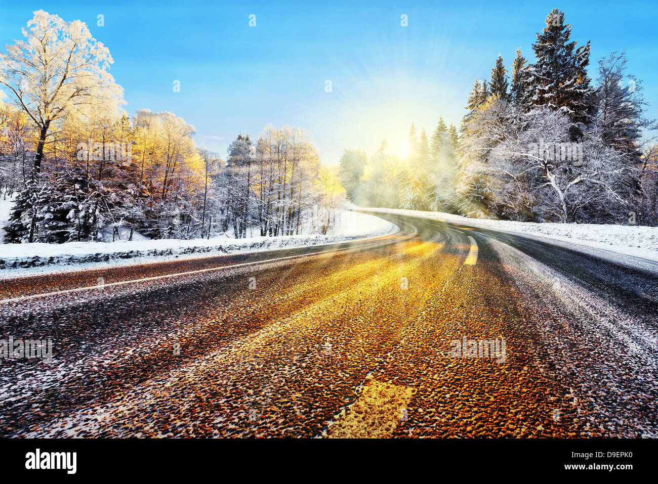 Winter road in winter with sunlight reflecting on asphalt Stock Photo