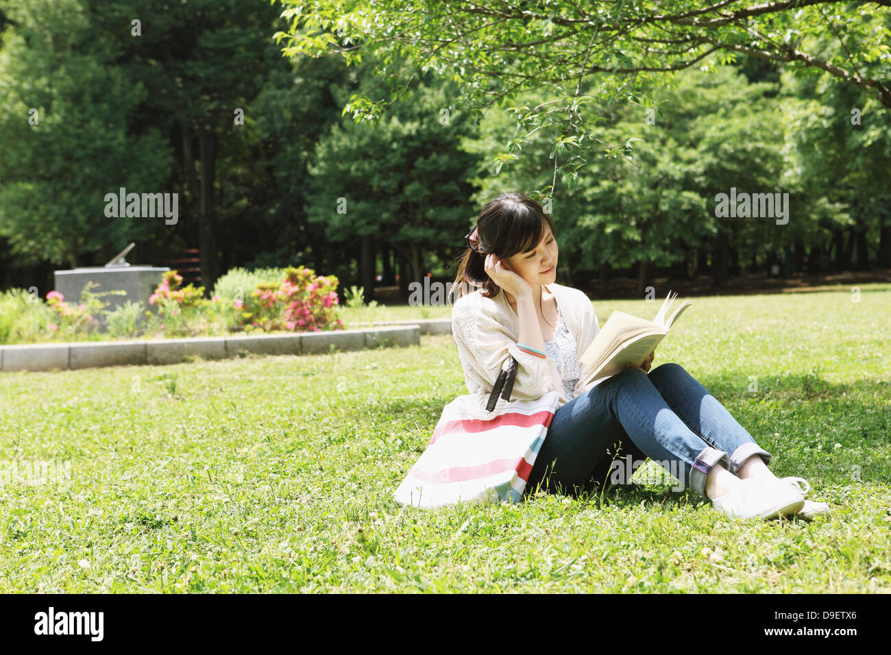 Female college student reading a book on grassland Stock Photo