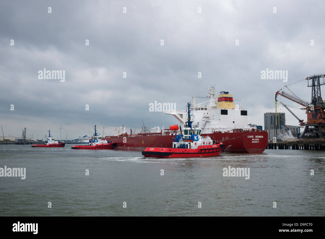 tugboats manoeuvring a supertanker ship into place in the port of Rotterdam, the Netherlands Stock Photo