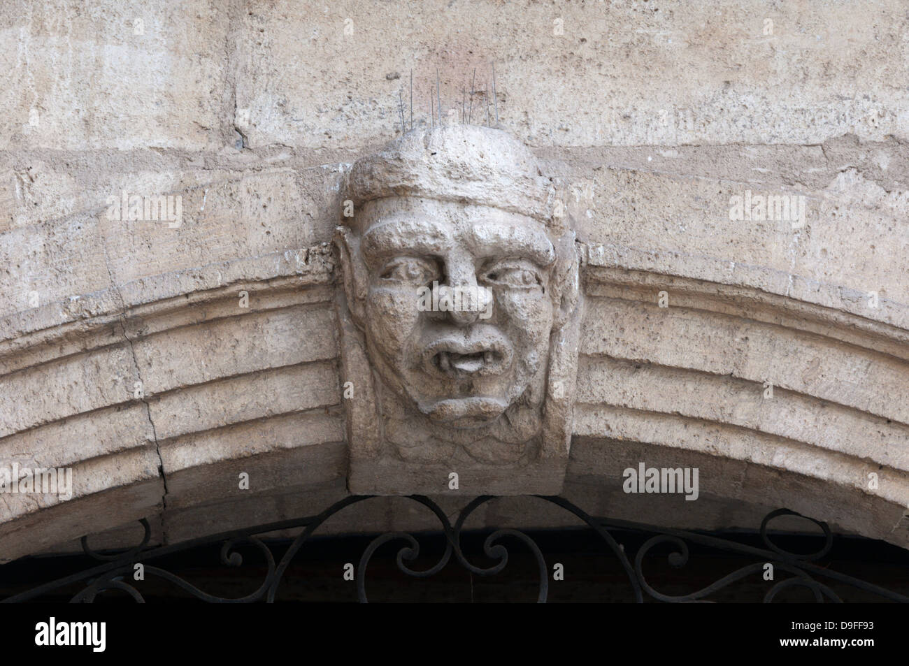 An ugly grotesque head carved over a doorway in the old French town of Pezenas. Stock Photo