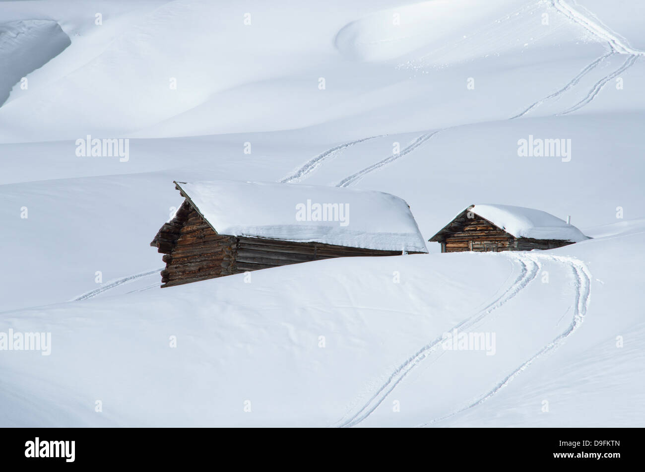 Two old wooden barns surrounded by deep snow and ski tracks in the Dolomites, South Tyrol, Italy Stock Photo