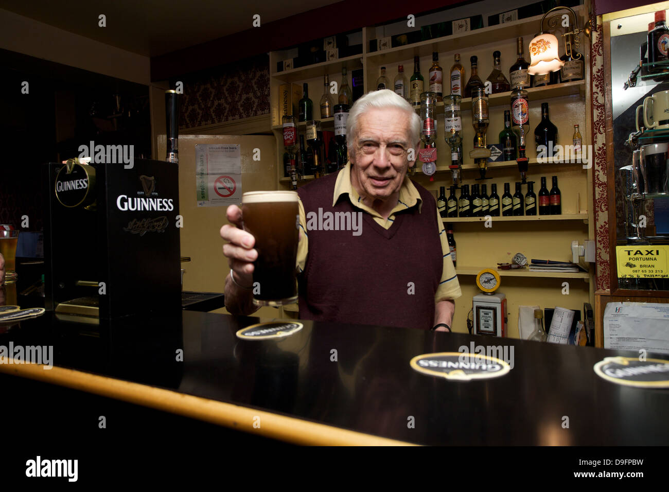 A barman handing over a pint of Guinness in a bar in County Galway Ireland Stock Photo