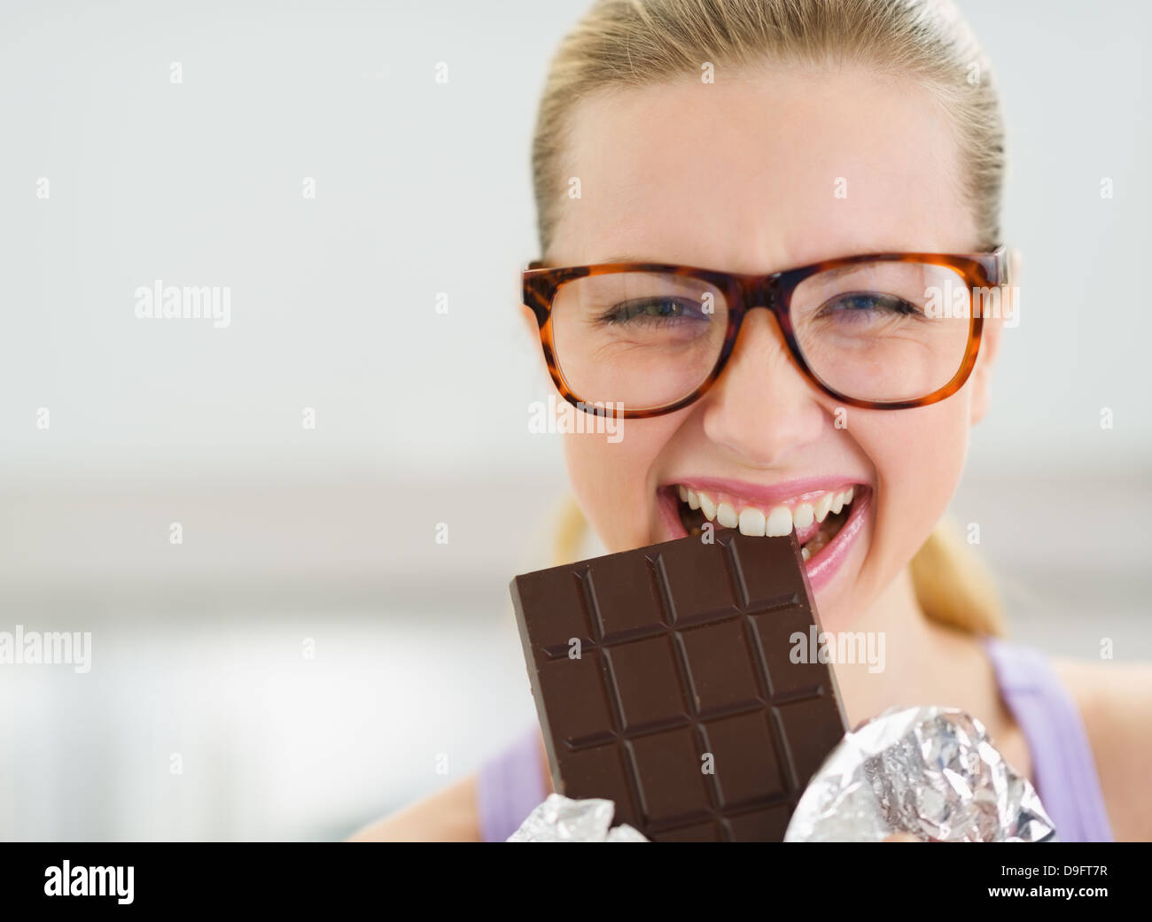 Happy teenage girl eating chocolate bar Stock Photo