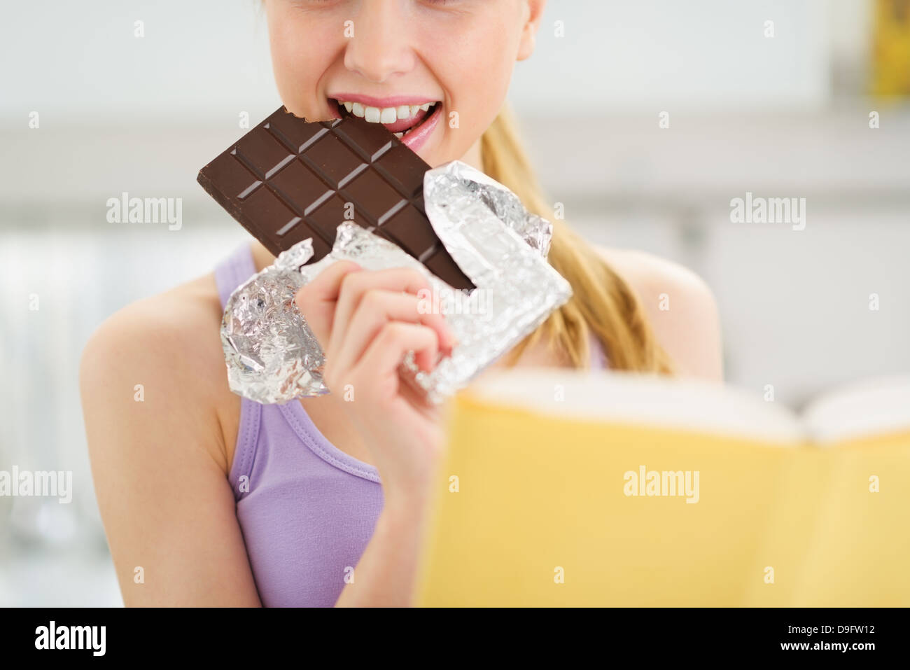 Closeup on teenage girl reading book and eating chocolate Stock Photo