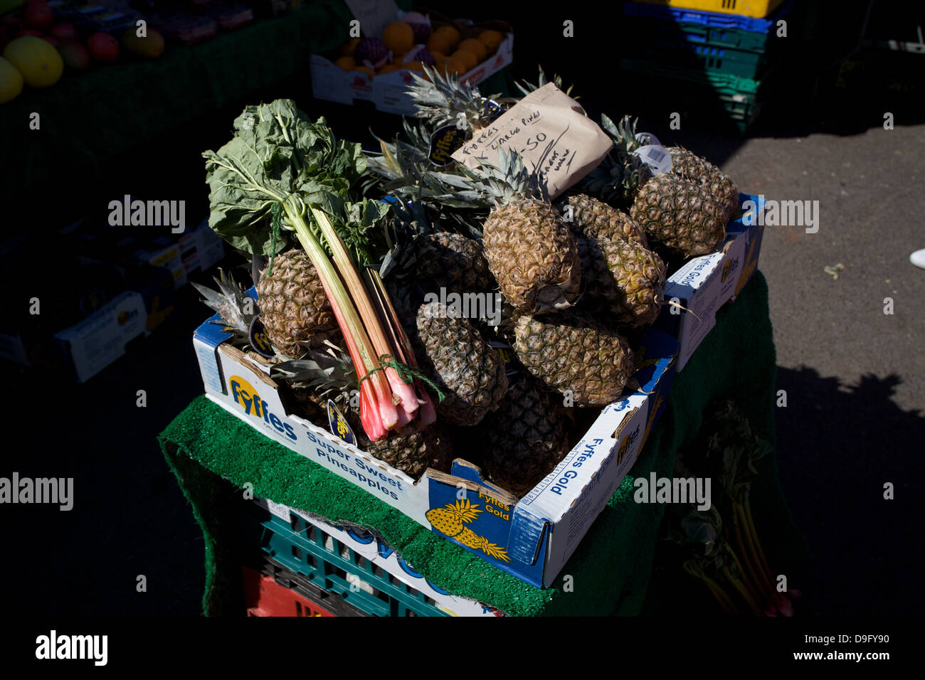 Pineapples and rhubarb for sale in a box at a farmers market. Stock Photo