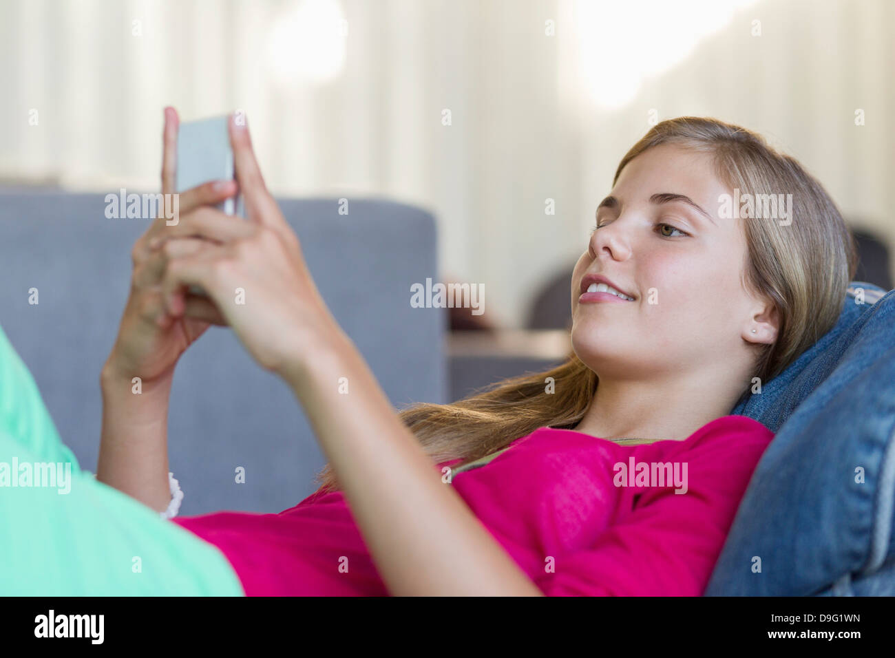 Girl lying on a bean bag and using a mobile phone Stock Photo - Alamy
