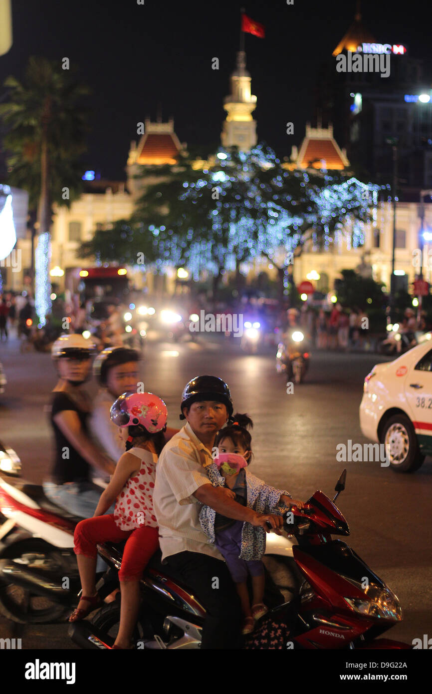 Ho Chi Minh City, Vietnam circa Jan 2013, An unidentified family of father and two dauthers gaze from a motorbike in the traffic Stock Photo