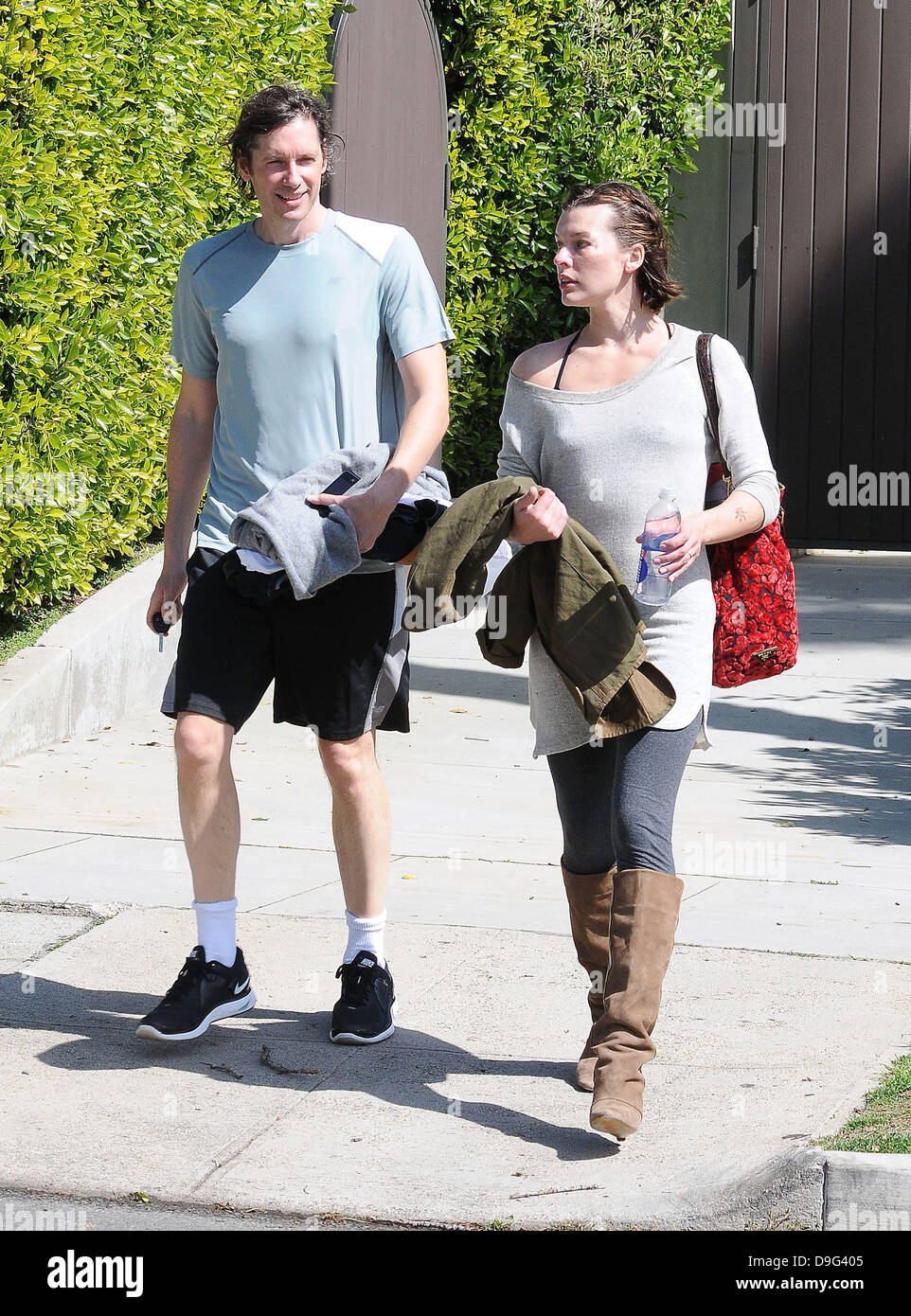 Milla Jovovich wearing brown knee length boots and t-shirt, leaving the