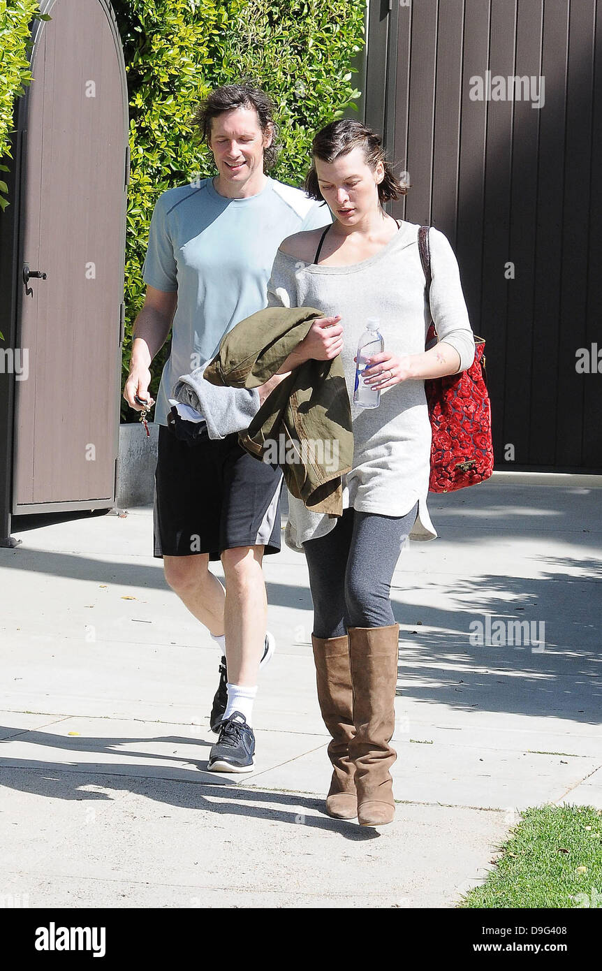 Milla Jovovich wearing brown knee length boots and t-shirt, leaving the