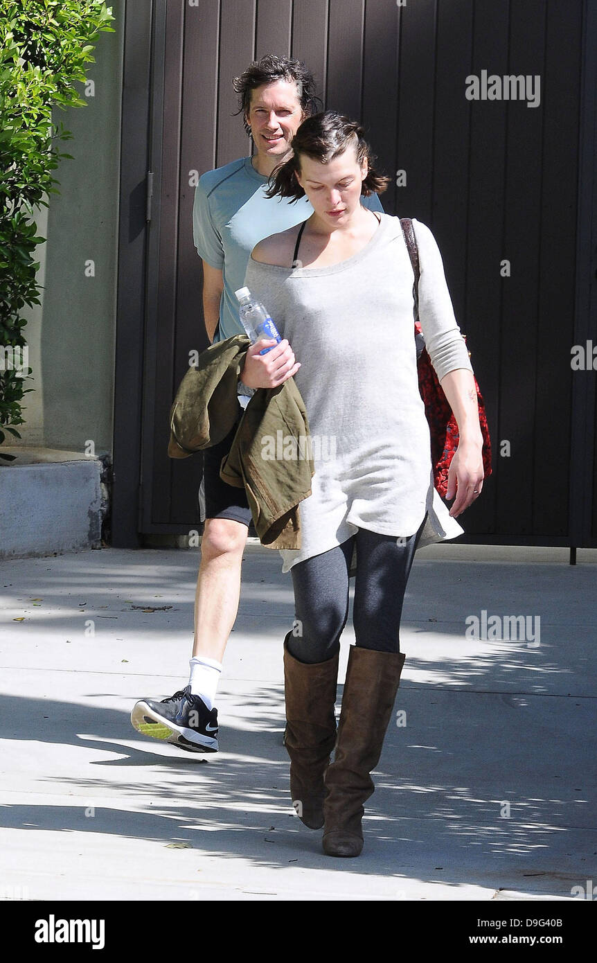 Milla Jovovich wearing brown knee length boots and t-shirt, leaving the