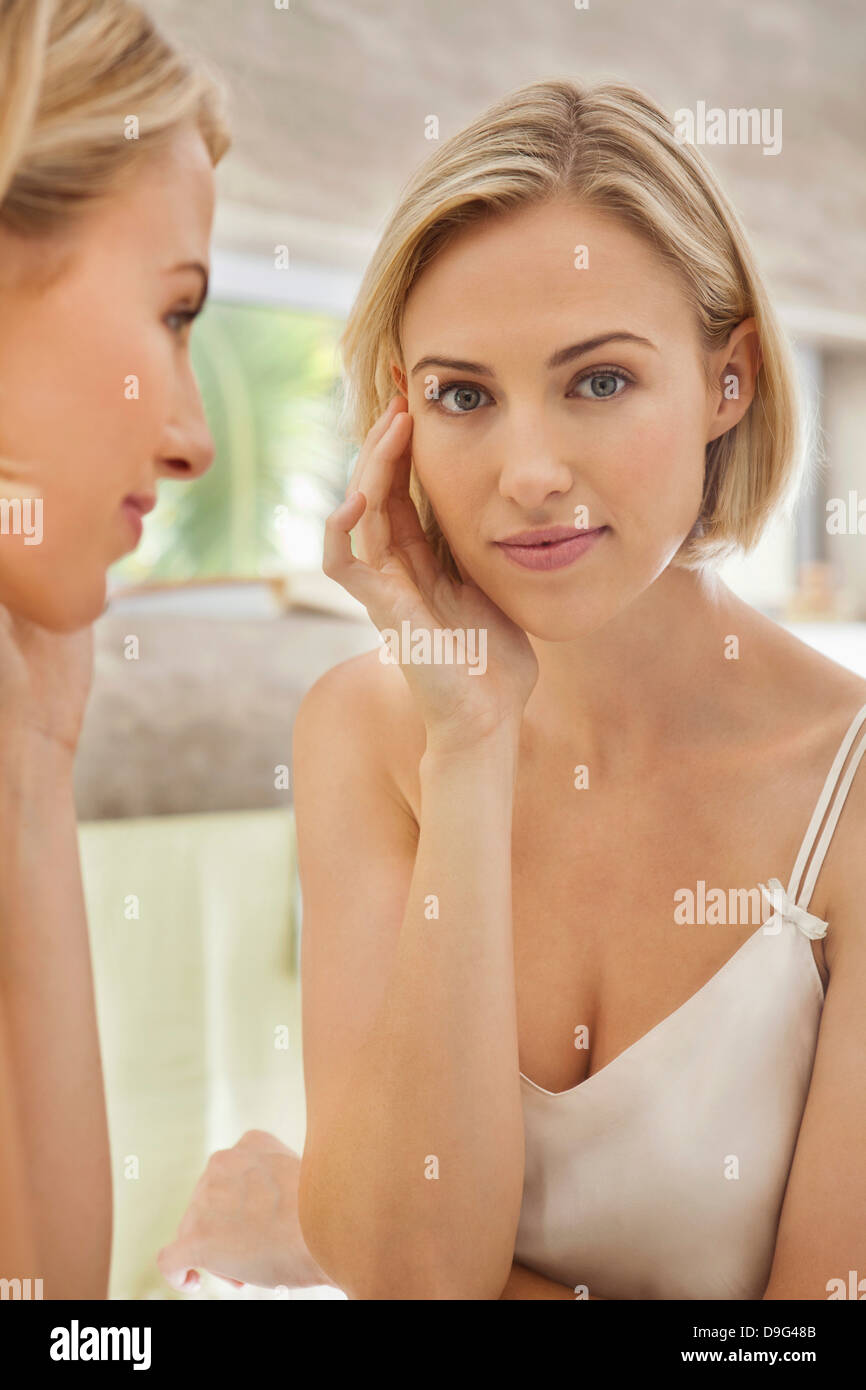 Woman checking her face in the mirror Stock Photo
