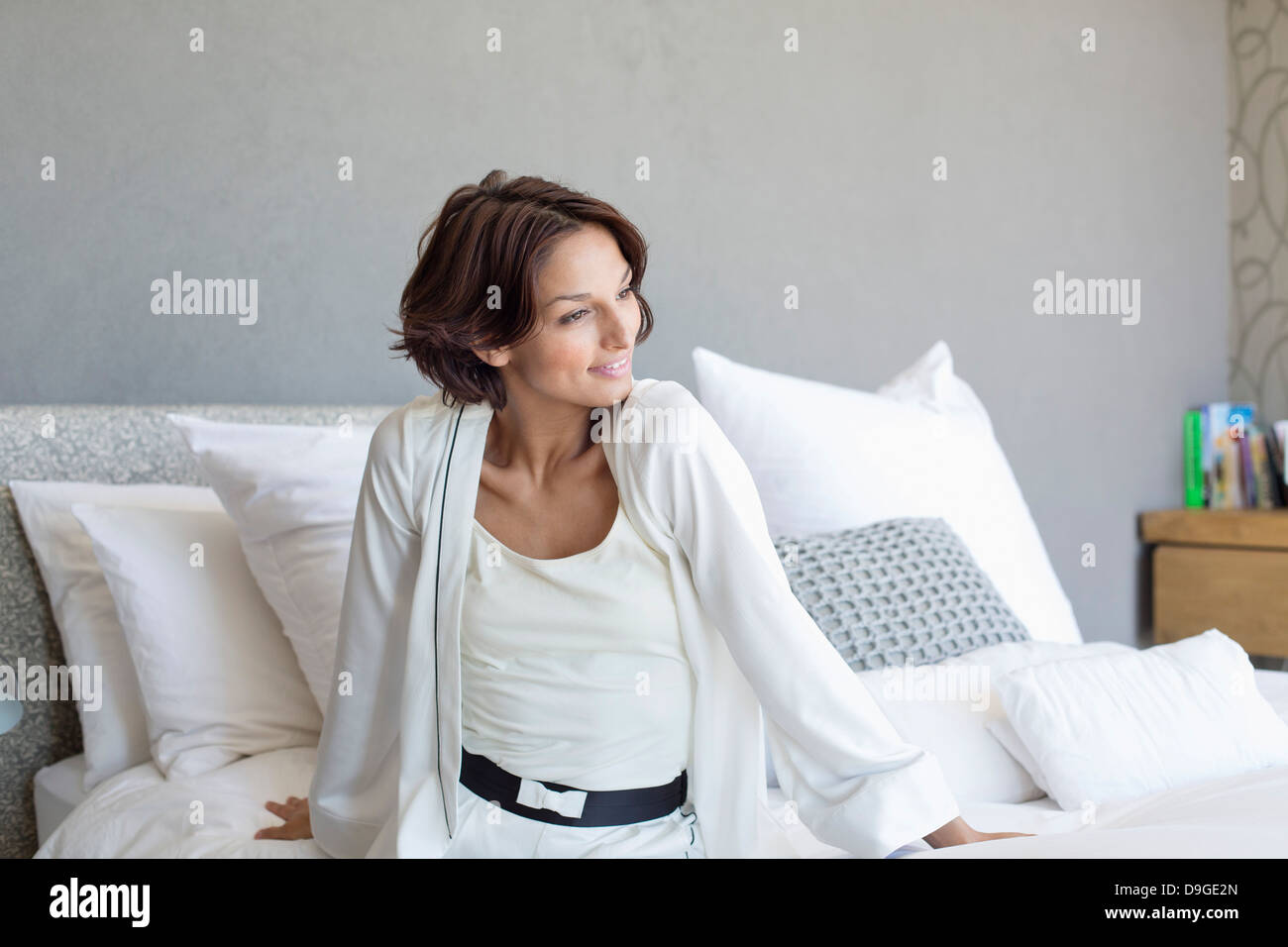 Woman sitting on the bed and smiling Stock Photo - Alamy
