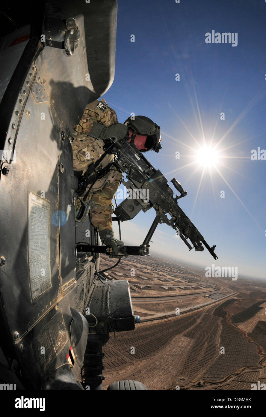 A US Army door gunner with the 25th Infantry Division scans for insurgents from a Black Hawk helicopter November 26, 2012 over Afghanistan's Kandahar province. Stock Photo