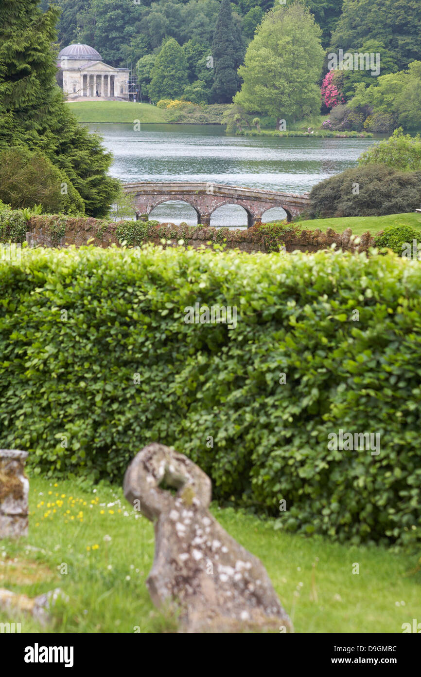 cemetery at church of St Peter's at Stourton, with Pantheon in Stourhead Gardens in the distance, Wiltshire in June Stock Photo