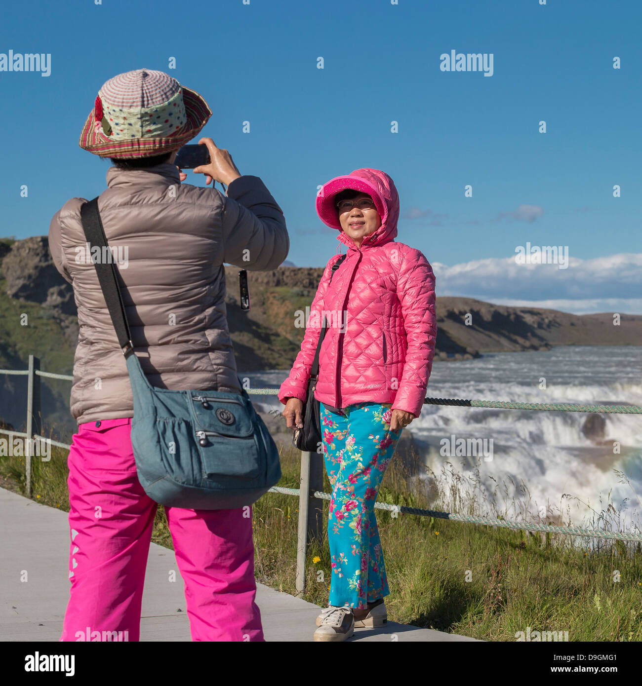 Asian woman taking pictures of each other Gullfoss Waterfalls, Iceland Stock Photo