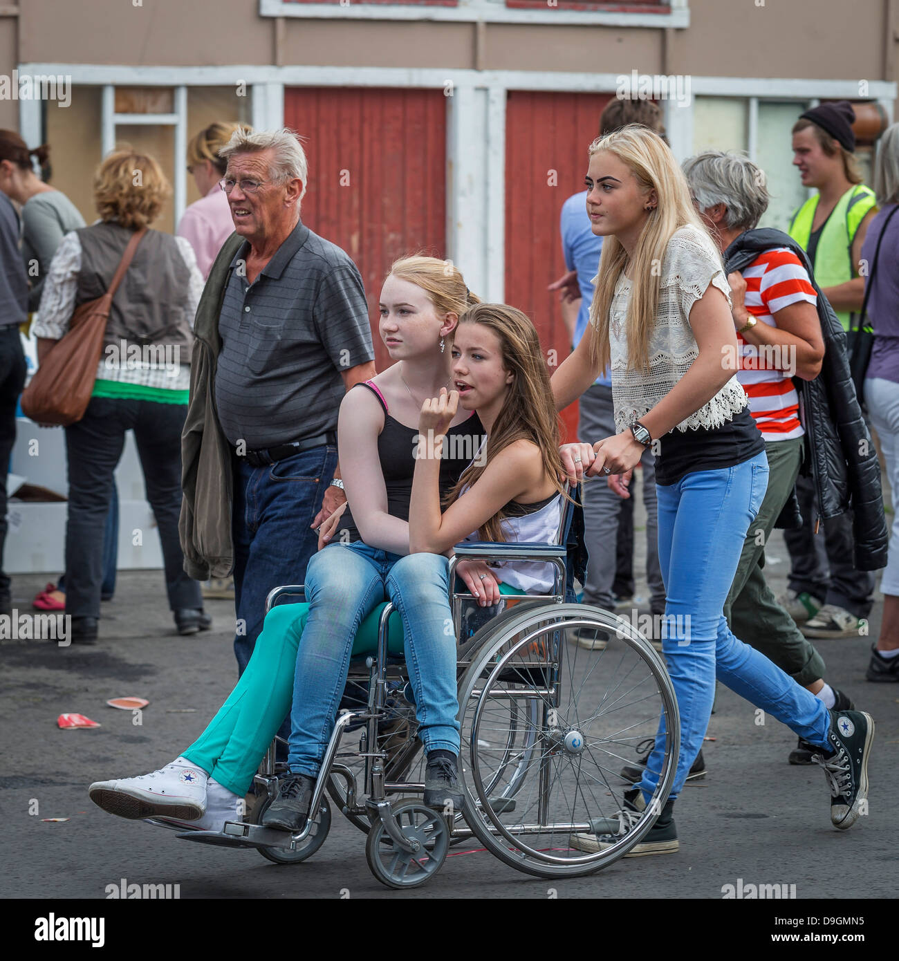 Girls using a wheel chair, summer festival, Dalvik, Iceland Stock Photo