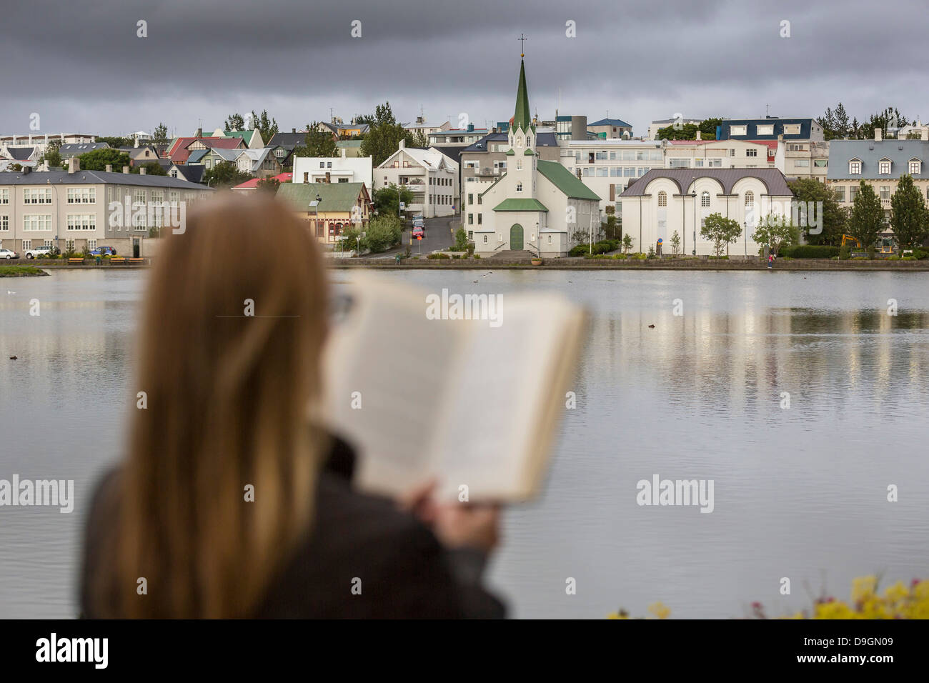 Woman reading next to statue of an Icelandic poet, Tomas Gudmundsson, Reykjavik, Iceland Stock Photo