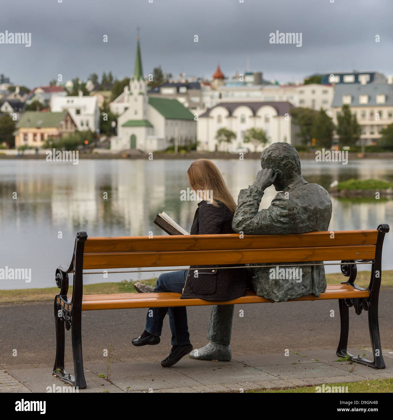 Woman reading next to statue of an Icelandic poet, Tomas Gudmundsson, Reykjavik, Iceland Stock Photo