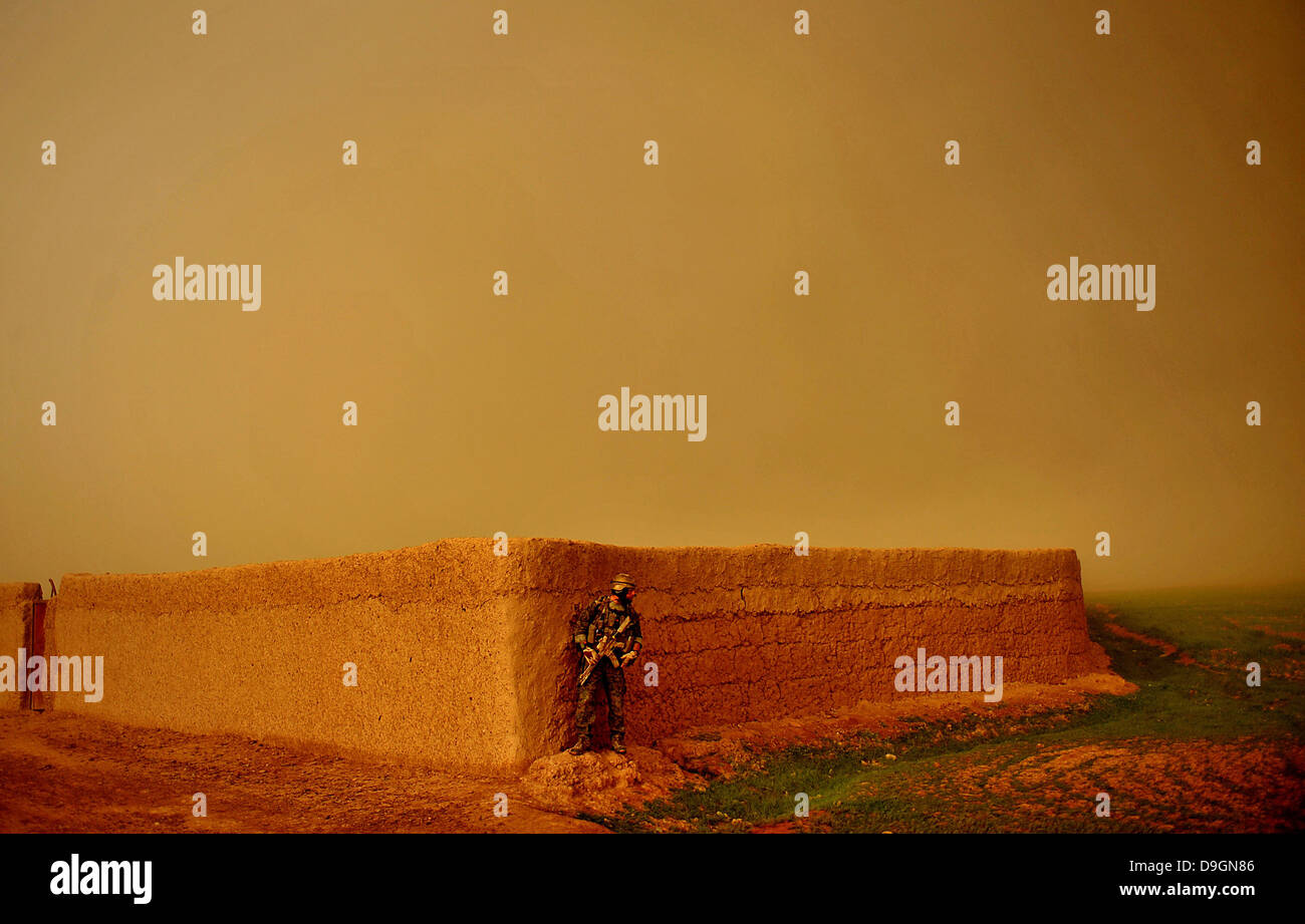 A US Marine Corps Special Operations commando takes cover behind a village wall as a sand storm approaches March 29, 2010 in Farah province, Afghanistan. Stock Photo