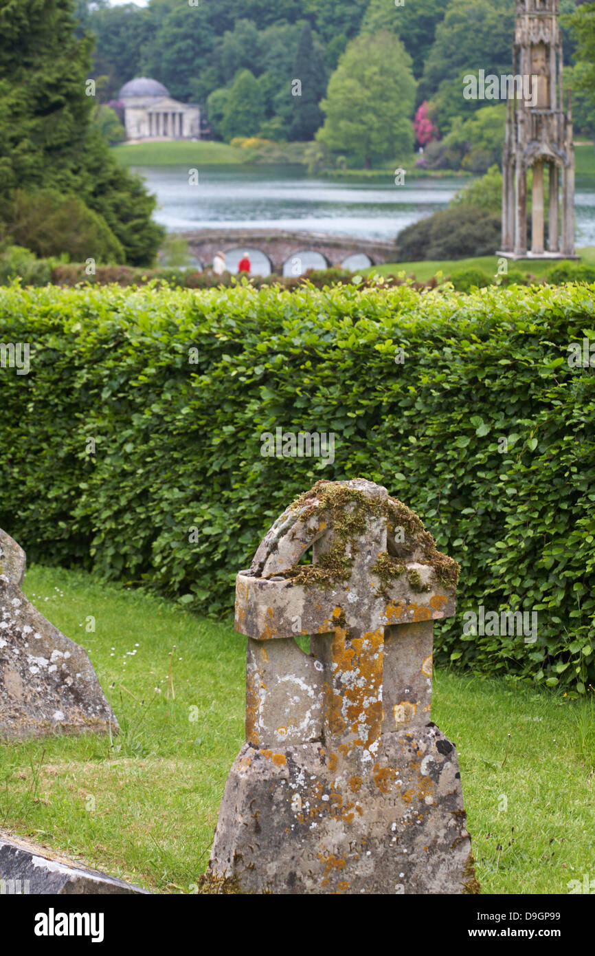 cemetery at church of St Peter's at Stourton, with Pantheon in Stourhead Gardens in the distance, Wiltshire in June Stock Photo