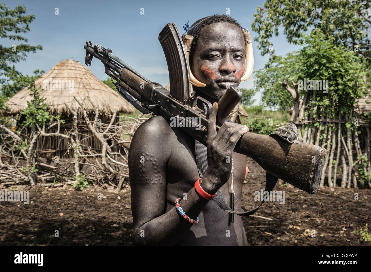 Portrait of a young mursi man holding a kalashnikov, Omo valley, Ethiopia Stock Photo