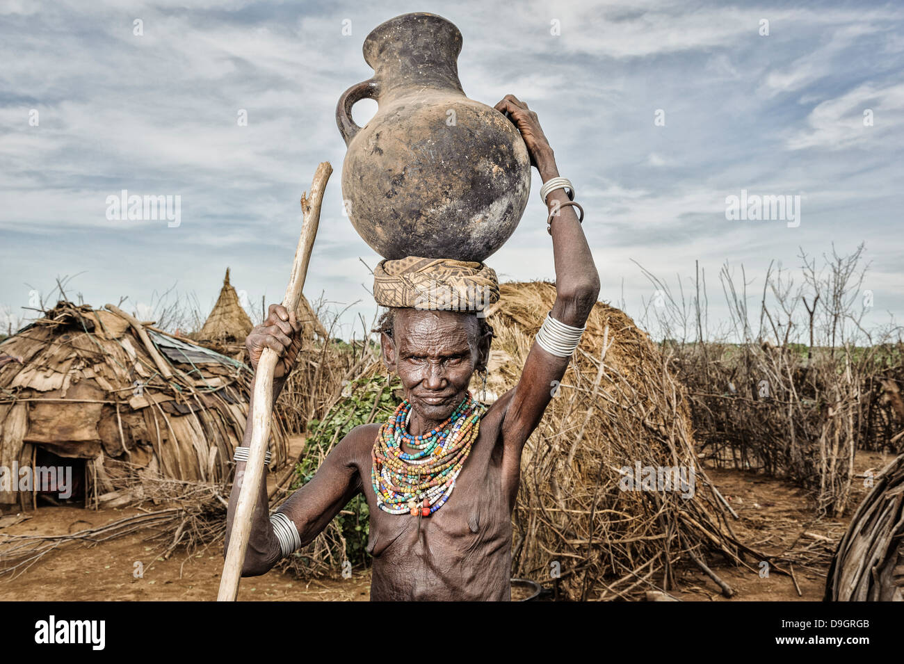 Old Dassanech woman carrying a big pot over her head near Omo river, Omorate, Ethiopia Stock Photo