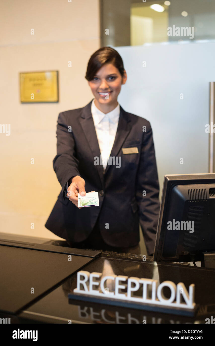 Receptionist holding a key card and smiling at the hotel reception