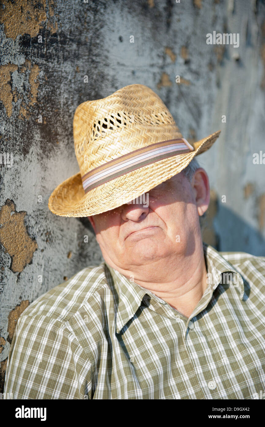 Senior man taking a siesta in the Mediterranean sunshine with his straw hat shielding his eyes. Stock Photo