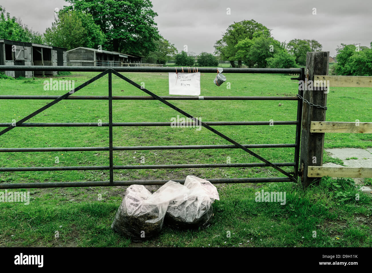 Two bags of horse manure for sale in front of a farm gate in rural Yorkshire. Coins are dropped in the honesty box. Stock Photo