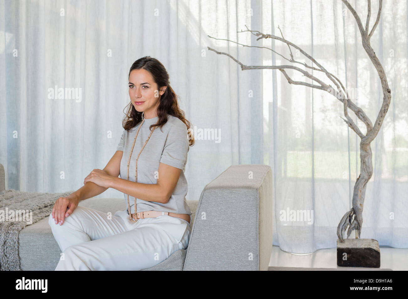 Beautiful woman sitting on a couch Stock Photo - Alamy