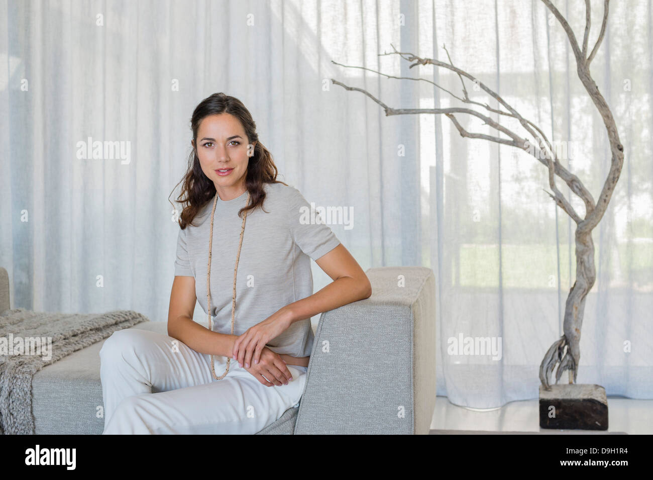 Portrait of a beautiful woman sitting on a couch Stock Photo - Alamy