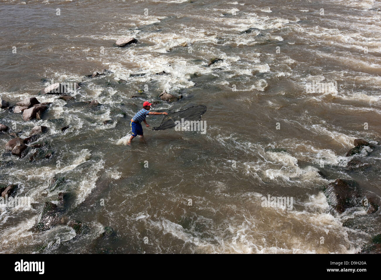 A man throws his fishing net near the dam of the river Dulce in Termas de Rio Hondo Stock Photo