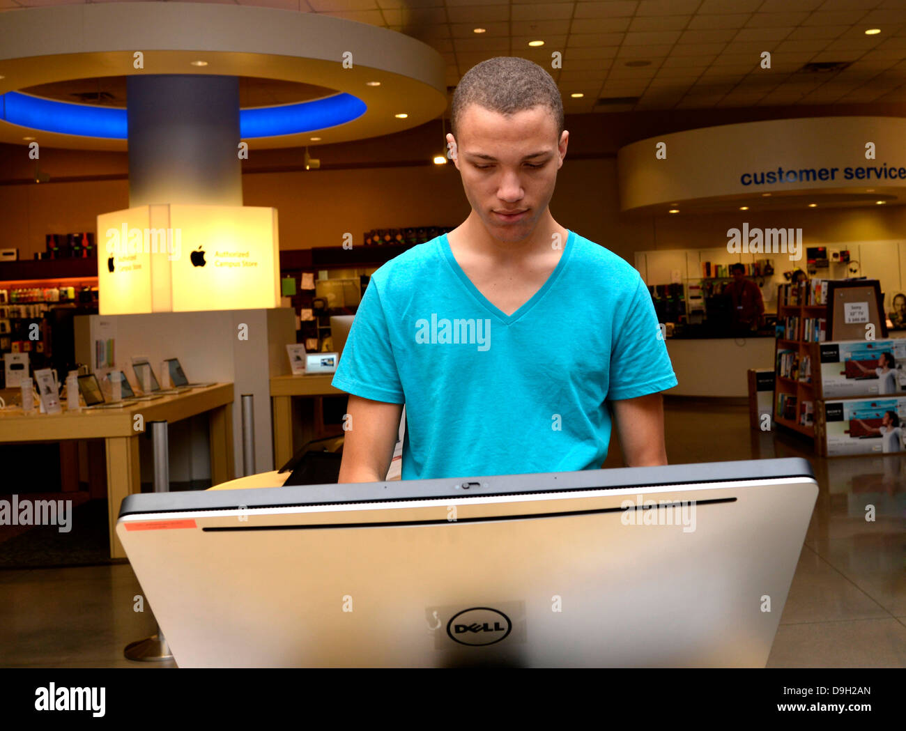 A young man looks at computers in a campus bookstore. Stock Photo