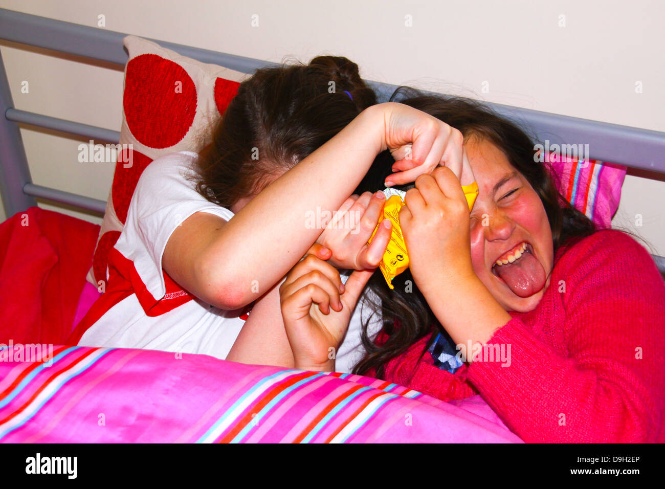 Sisters playing and laughing in bed Stock Photo