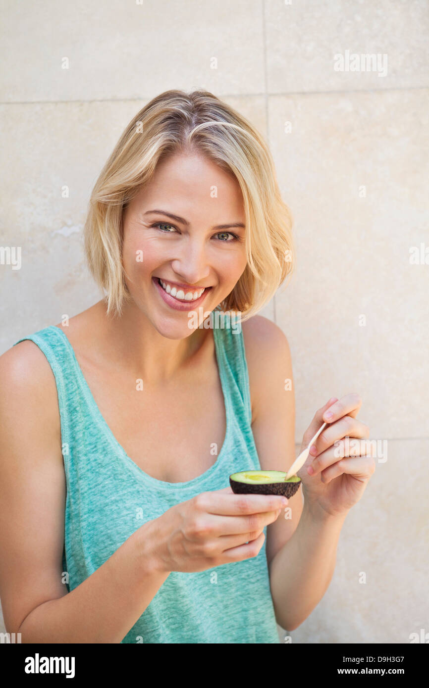 Portrait of a smiling woman eating avocado Stock Photo