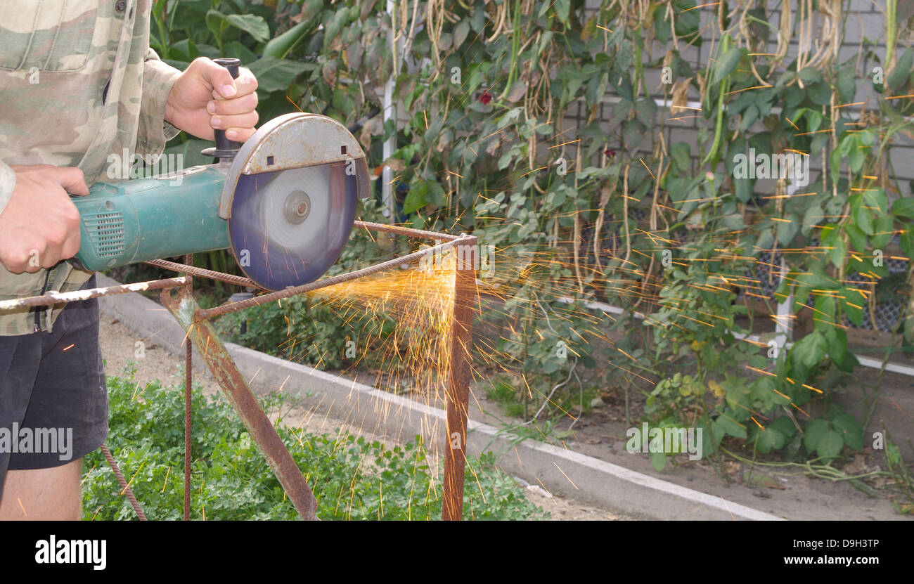 Angle Grinder Metal sawing with flashing sparks close up and Repairman hands home repair garden working summer time Stock Photo