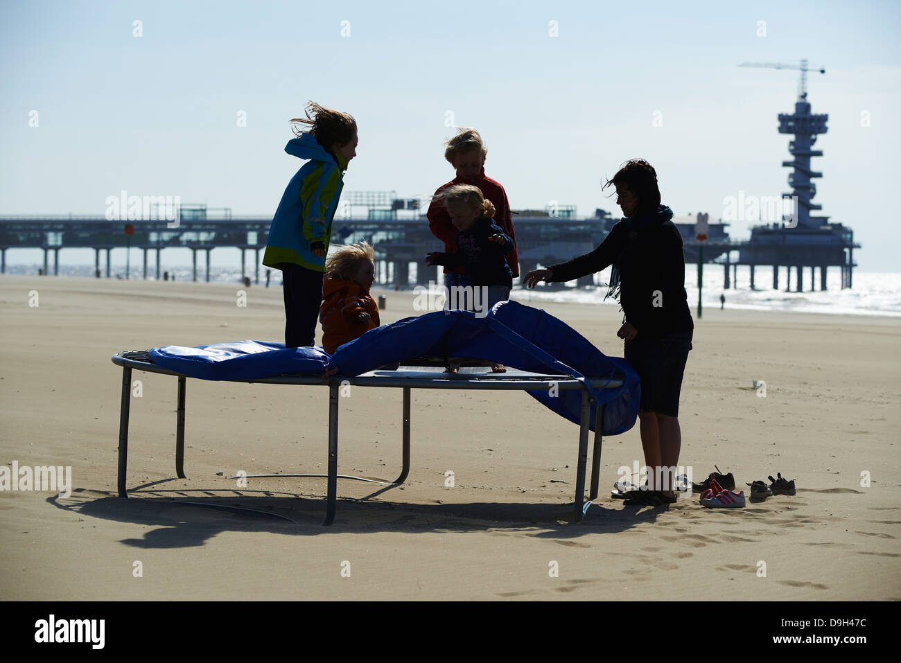 The pier in Scheveningen the Netherlands as seen from the beach. Children  playing and jumping on trampoline with mothers Stock Photo - Alamy