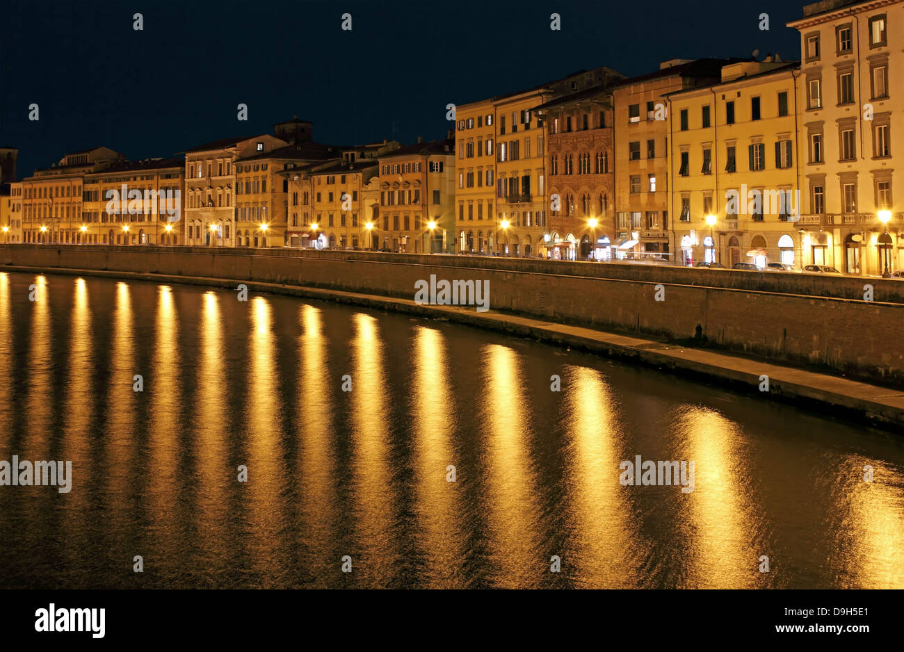 Night View of Pisa riverbank with bright lamp post reflections over river Arno. Stock Photo