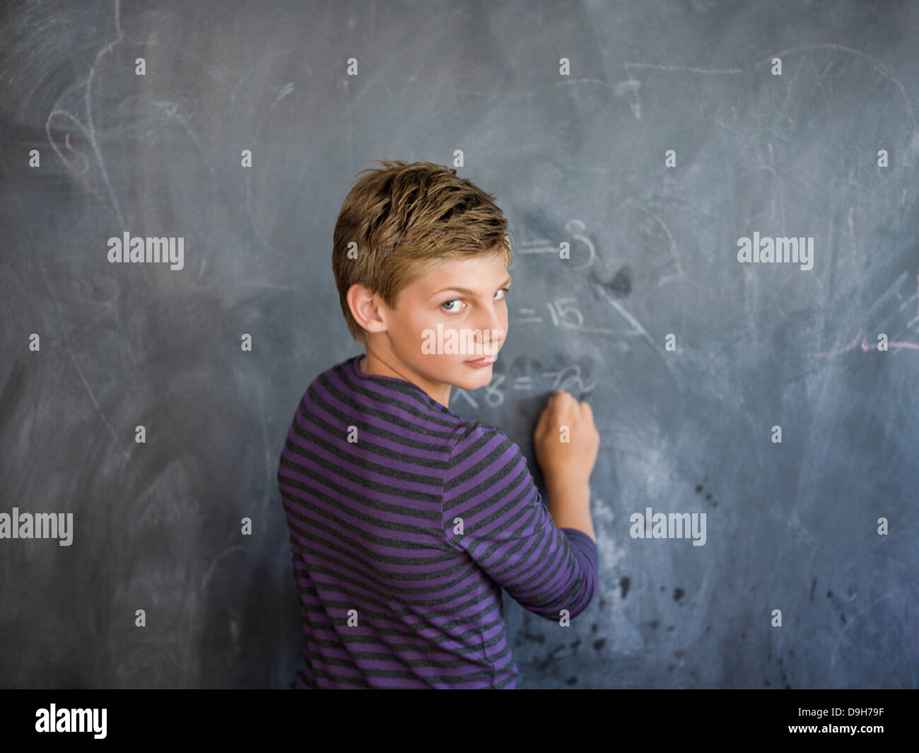Boy writing on a blackboard in a classroom Stock Photo