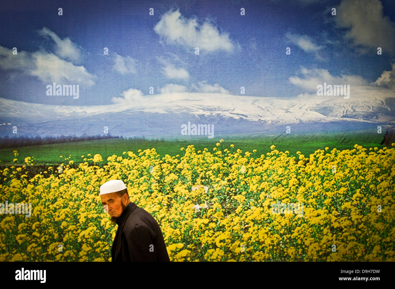 A Muslim man walks by a poster in Xining, China Stock Photo