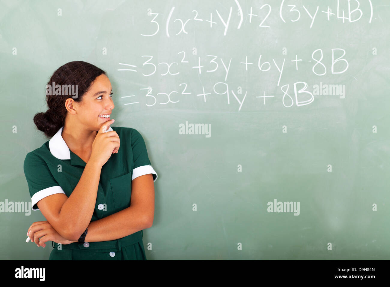 happy female high school student in classroom looking at maths writing on the blackboard Stock Photo